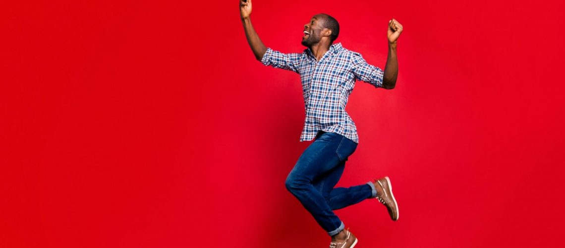 Full length body size profile side view of nice funny crazy handsome cheerful guy wearing checkered shirt holding in hands cell reading text going in air isolated on bright vivid shine red background