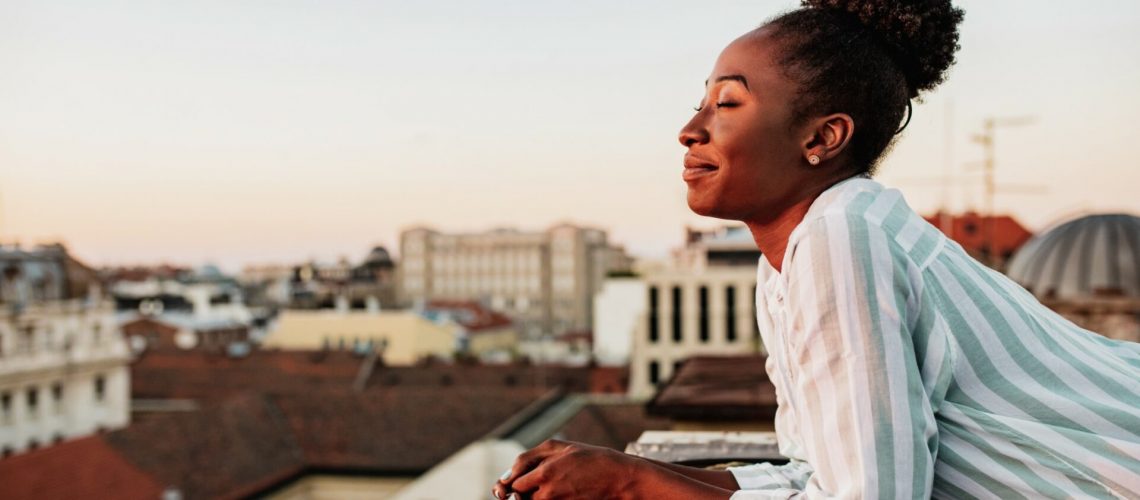 Young African American woman is on the balcony at sunset